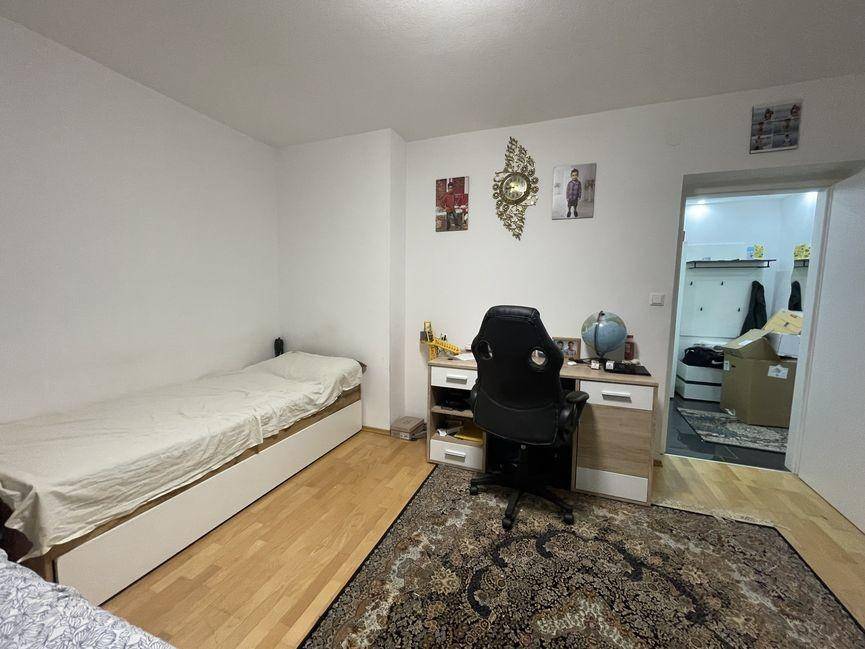 Schlafzimmer mit Einzelbett, Schreibtisch und Zugang zu einem angrenzenden Raum.