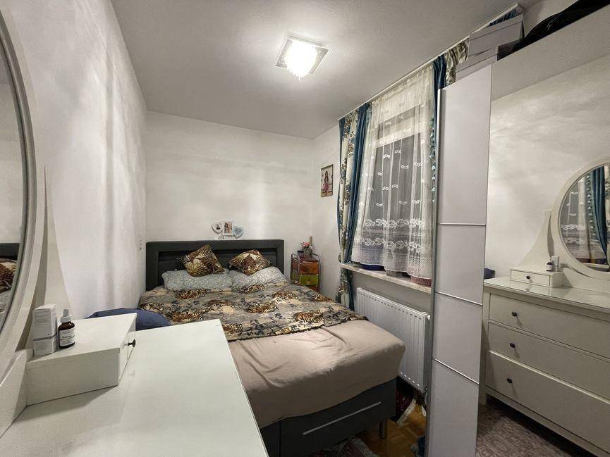 Schlafzimmer mit Doppelbett, Schminktisch und Fenster mit Vorhängen.