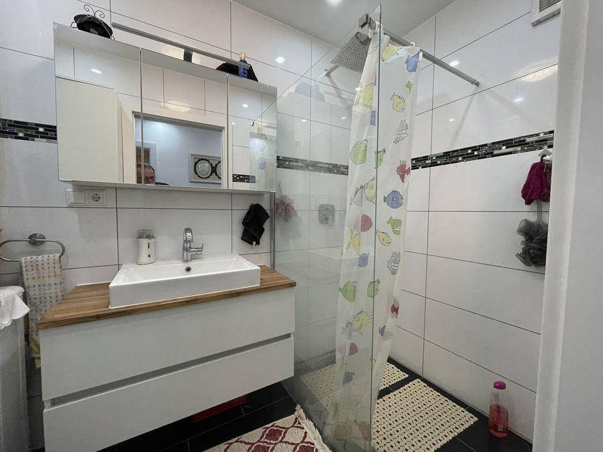 Modernes Badezimmer mit Duschkabine, Waschbeckenunterschrank und Spiegelschrank.