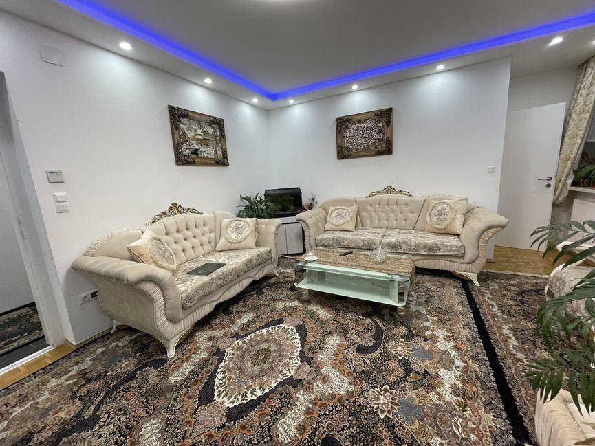 Geräumiges Wohnzimmer mit bequemen Sofas, einem großen Teppich und stimmungsvoller Deckenbeleuchtung.