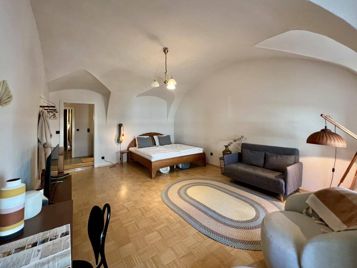 Helles Schlafzimmer mit Holzbett, Sofa und Parkettboden.