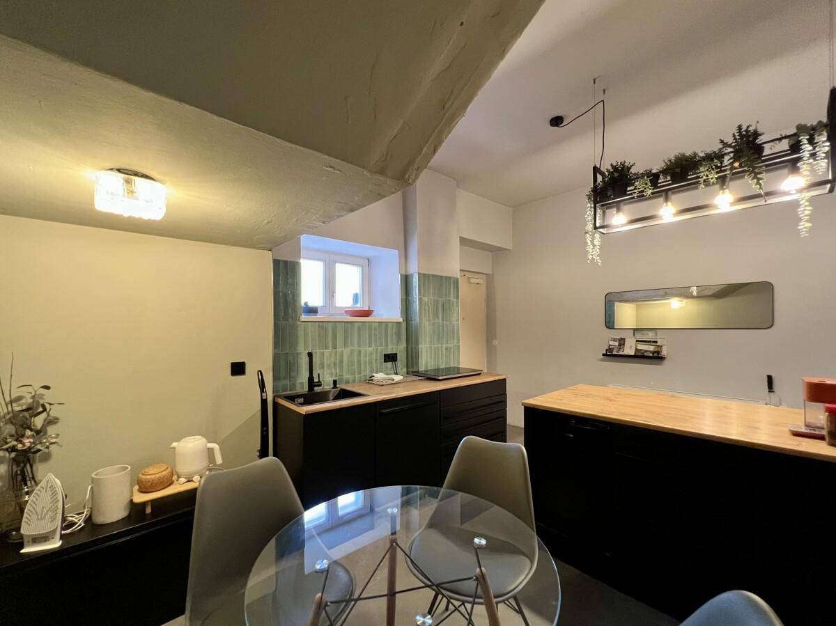 Moderne Küche mit schwarzen Schränken, Holztheke und Essbereich.