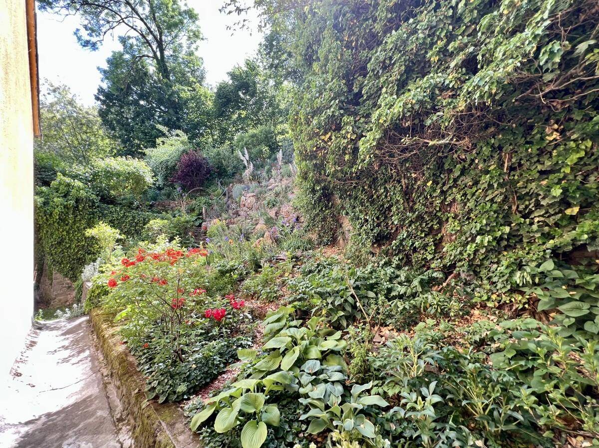 Üppiger Garten mit vielfältiger Bepflanzung und Natursteinmauern.