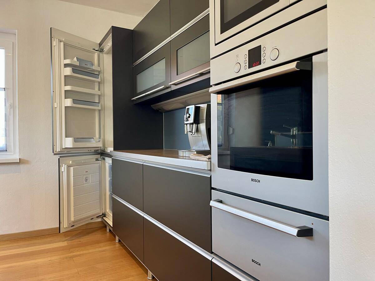 Hochwertige Einbauküche mit integriertem Kühlschrank, Backofen und Kaffeemaschine.