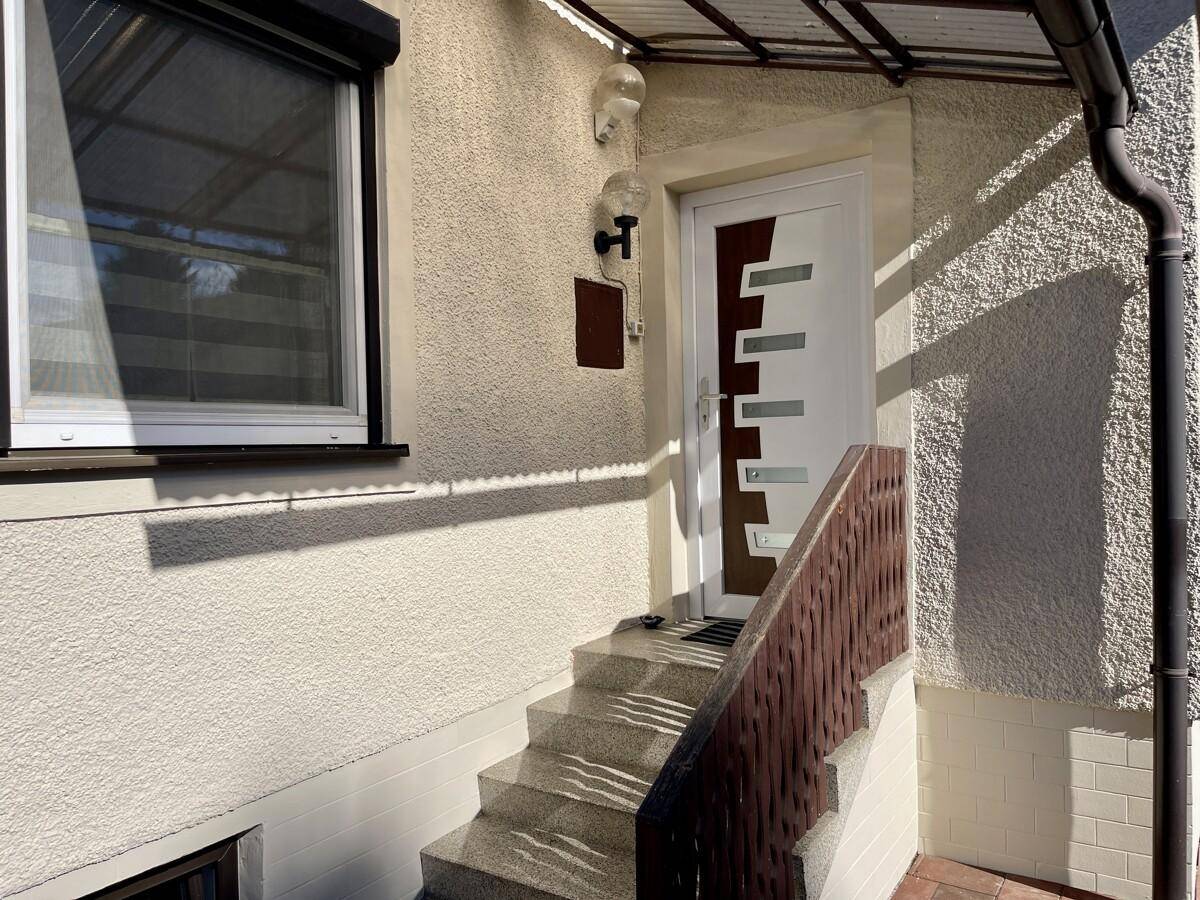 Eingangsbereich des Hauses mit moderner Haustür und Treppenzugang.