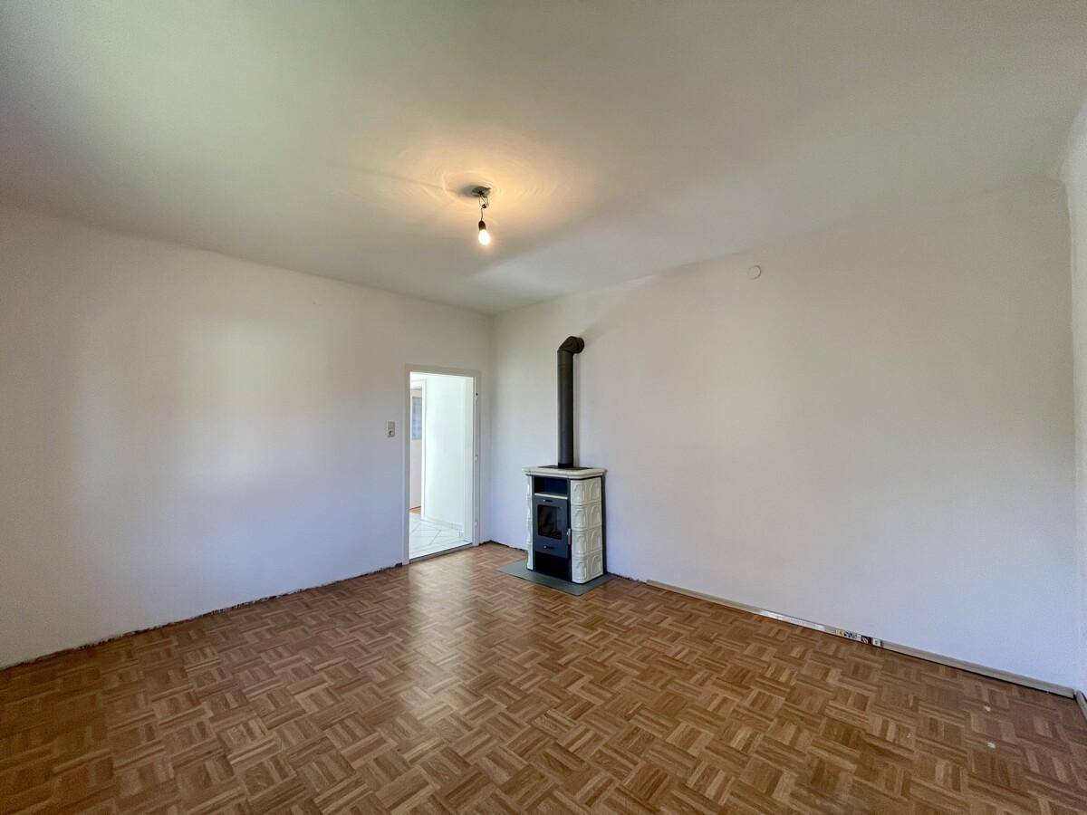 Geräumiges Wohnzimmer mit Parkettboden und einem gemütlichen Kaminofen.