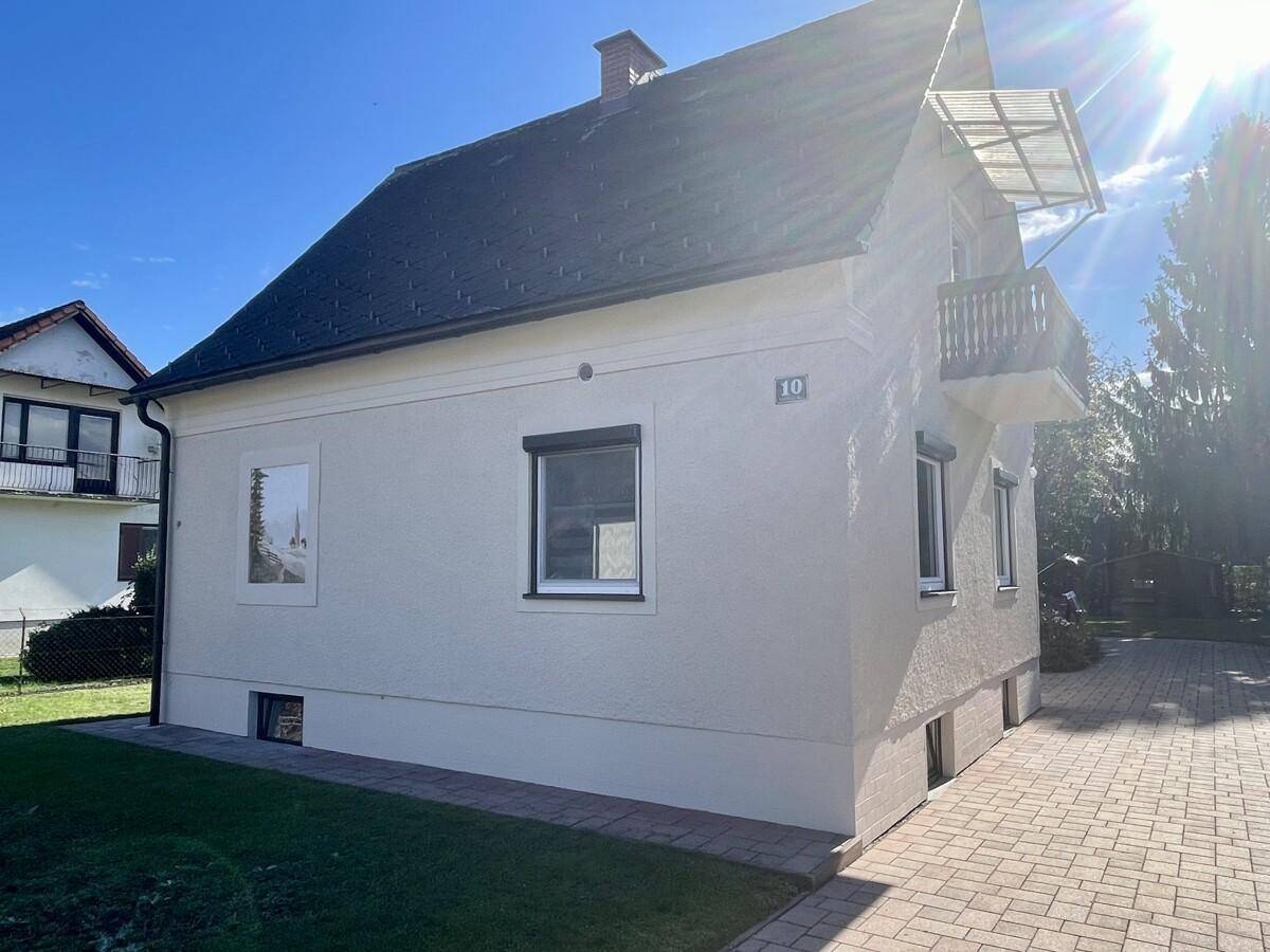 Seitenansicht des Hauses mit Balkon, Rollläden und gepflegter Fassade.