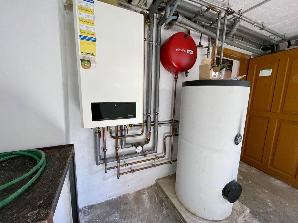 Detailansicht der modernen Gasheizung und des Warmwasserspeichers im Technikraum.