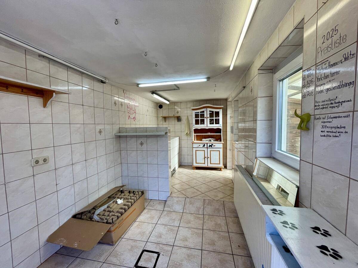 Gefliester Raum mit Arbeitsflächen und Fenster, möglicherweise als Werkstatt oder Lager genutzt.