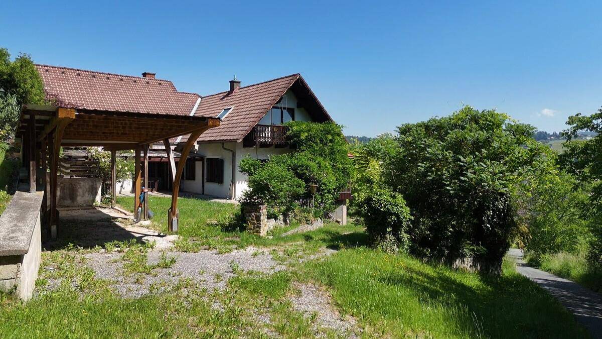 Haus mit Carport und weitläufigem Grundstück, umgeben von viel Grün und Natur.