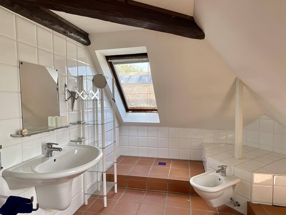 Helles Badezimmer im Dachgeschoss mit Fliesen, Waschbecken, Bidet und Dachfenster.
