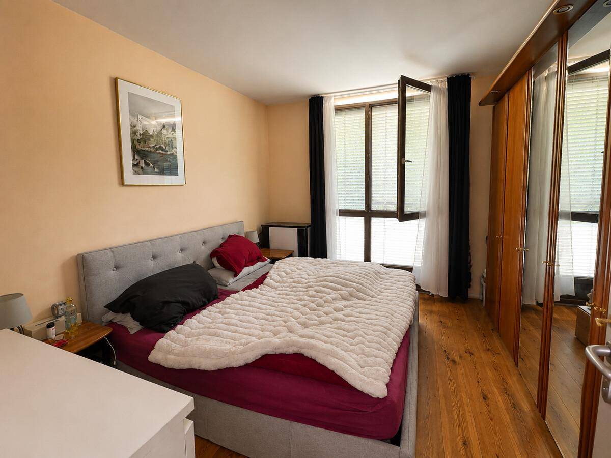 Gemütliches Schlafzimmer mit Doppelbett, Holzboden und großem Spiegelschrank.