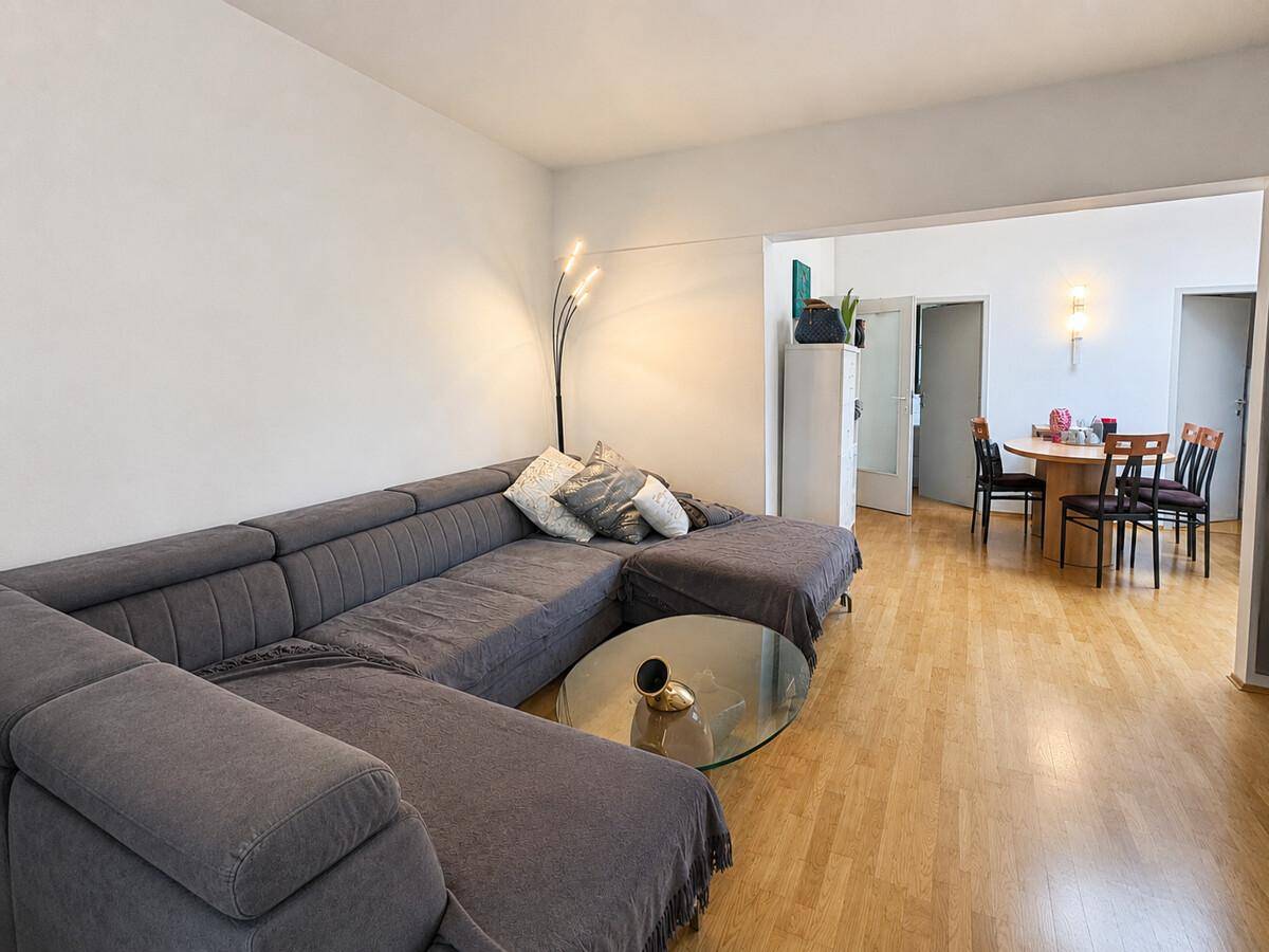 Geräumiger Wohn-Essbereich mit großem Ecksofa, Holzboden und Essbereich im Hintergrund.