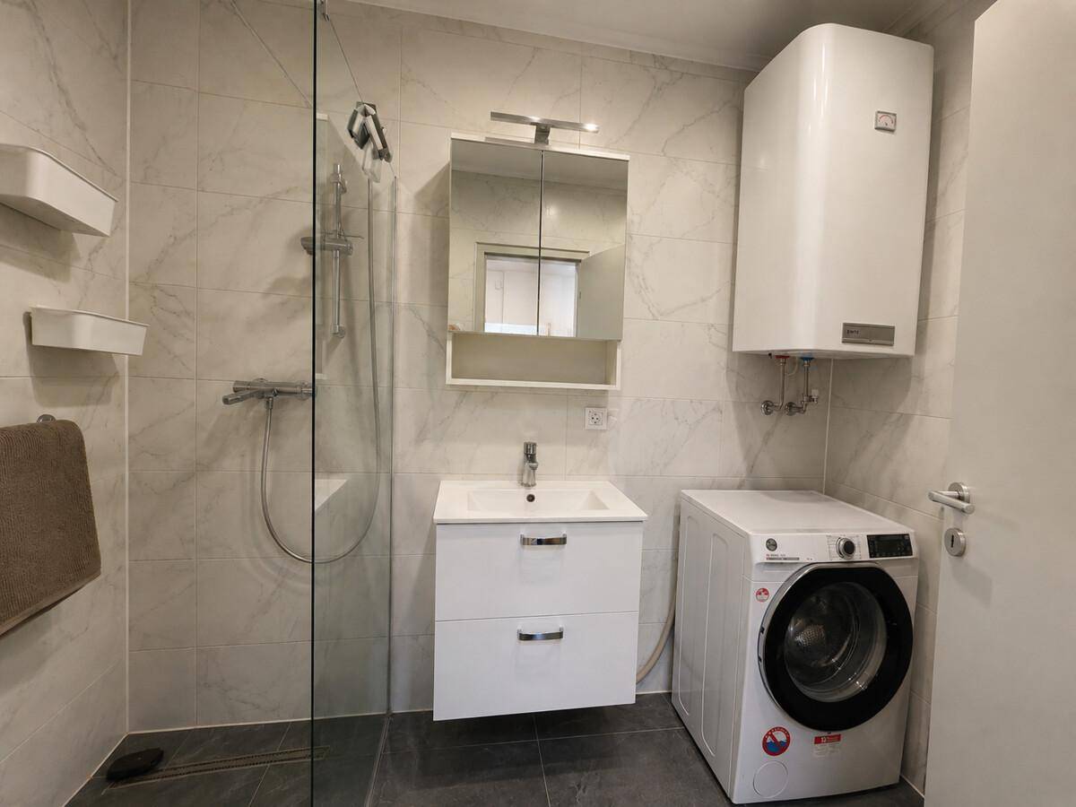 Modernes Badezimmer mit begehbarer Dusche, Waschbecken und Waschmaschine.