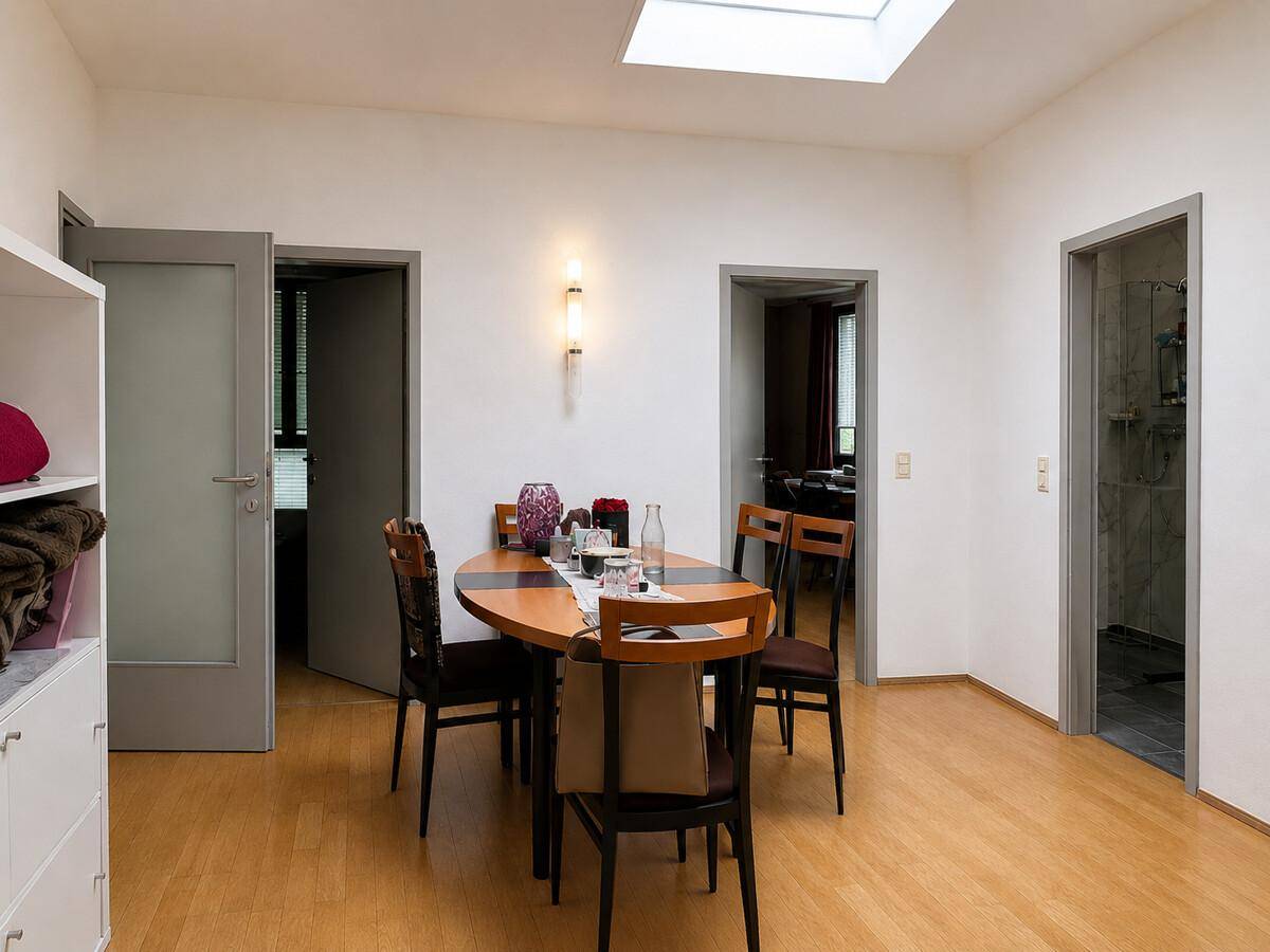 Heller Essbereich mit Holztisch, Stühlen und Oberlicht für natürliches Licht.