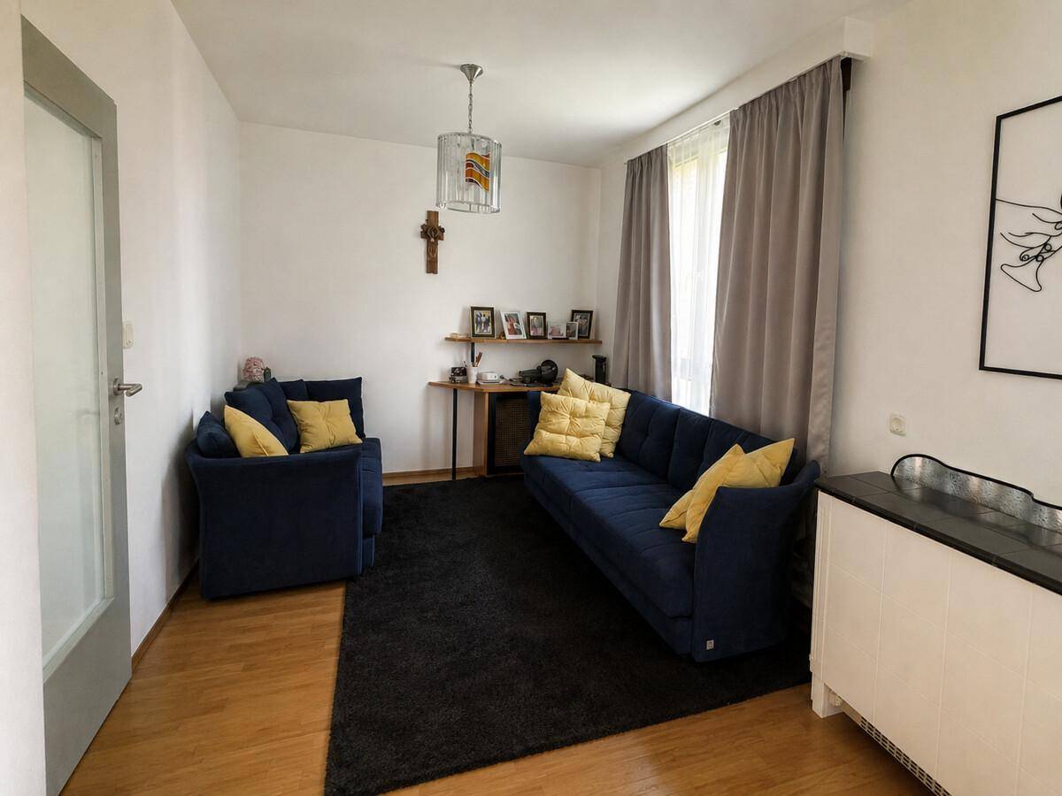 Gemütliches Wohnzimmer mit blauen Sofas, Teppich und Holzboden.