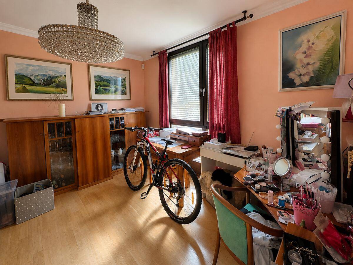 Vielseitiger Raum mit Schreibtisch, Fahrrad und Kronleuchter, genutzt als Büro.