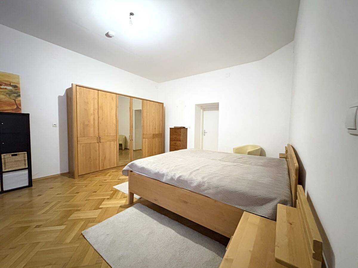 Geräumiges Schlafzimmer mit Holzbett, Parkettboden und großem Spiegelschrank.