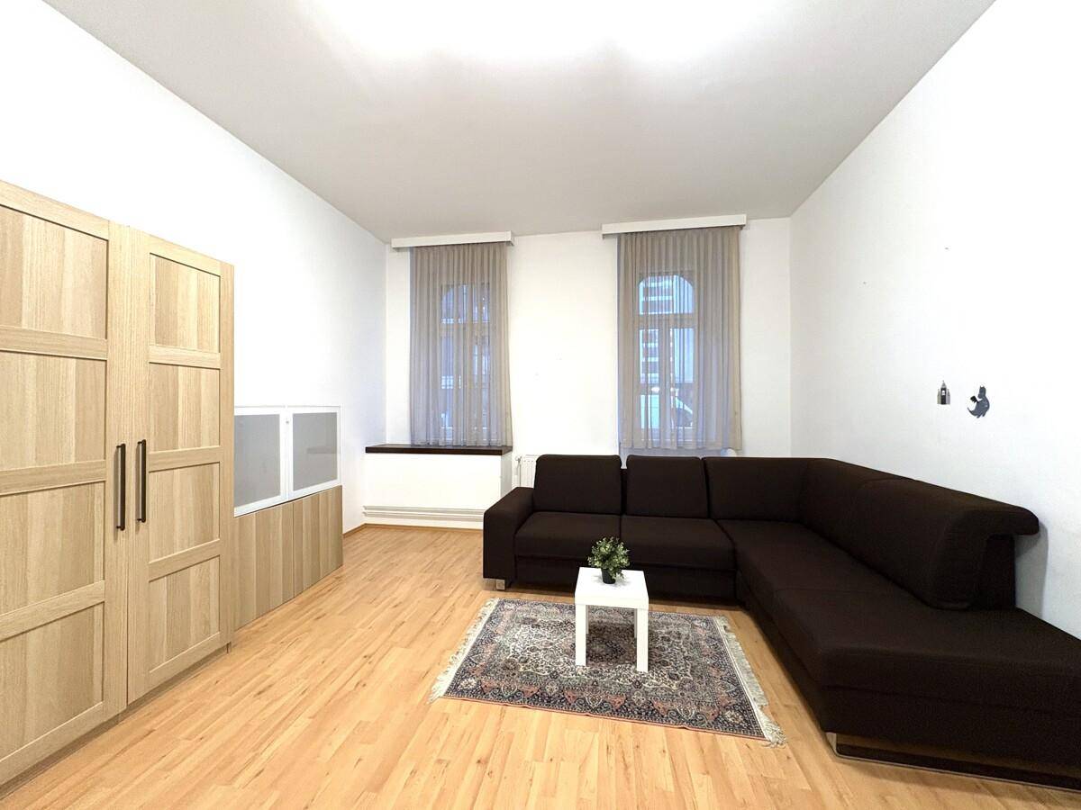 Gemütliches Wohnzimmer mit großem Ecksofa, Holzboden und hellen Fenstern.