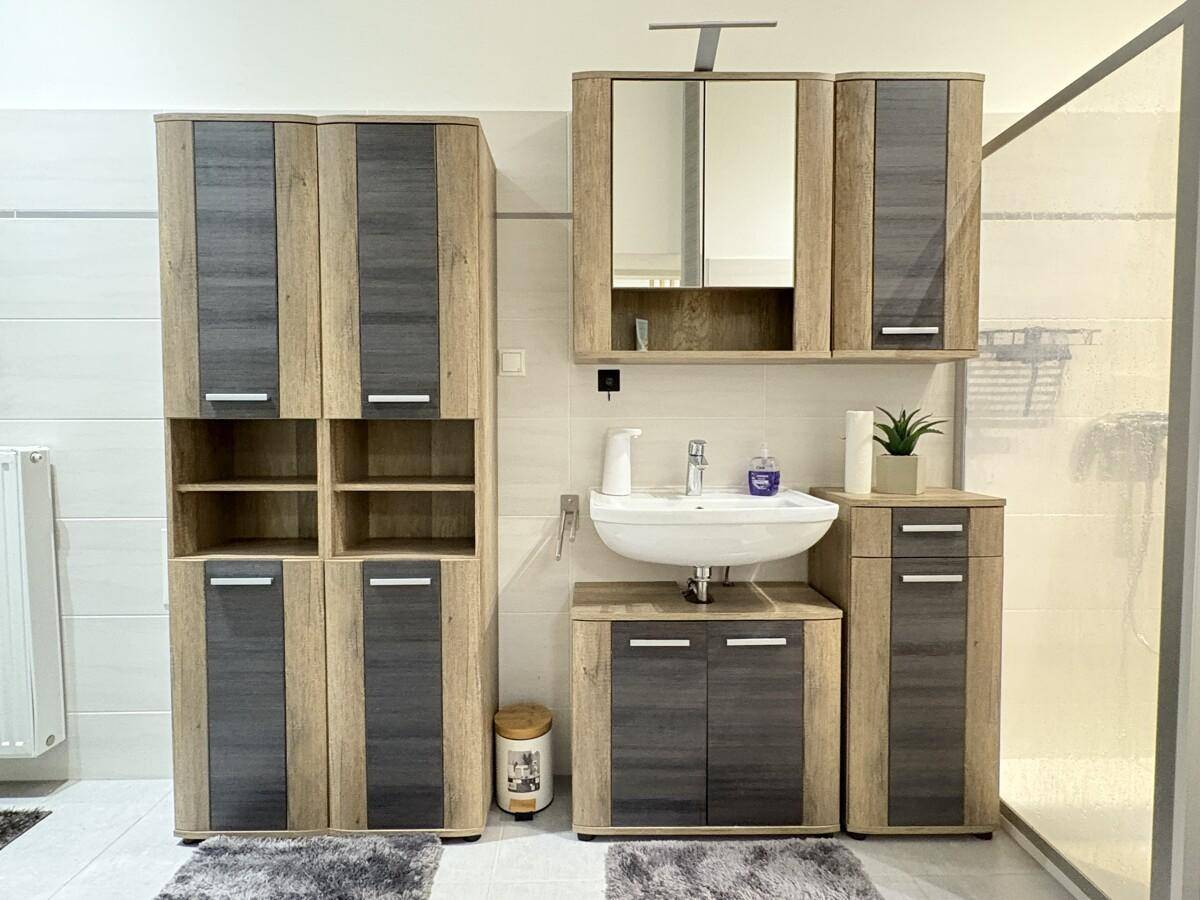 Badezimmer mit modernem Waschtisch, Spiegelschrank und viel Stauraum in Holzoptik.