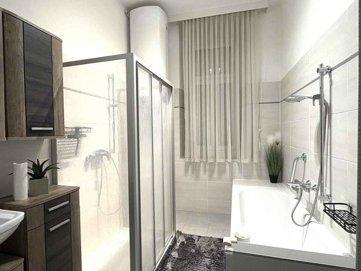 Modernes Badezimmer mit Badewanne, Duschkabine und hellen Fliesen.