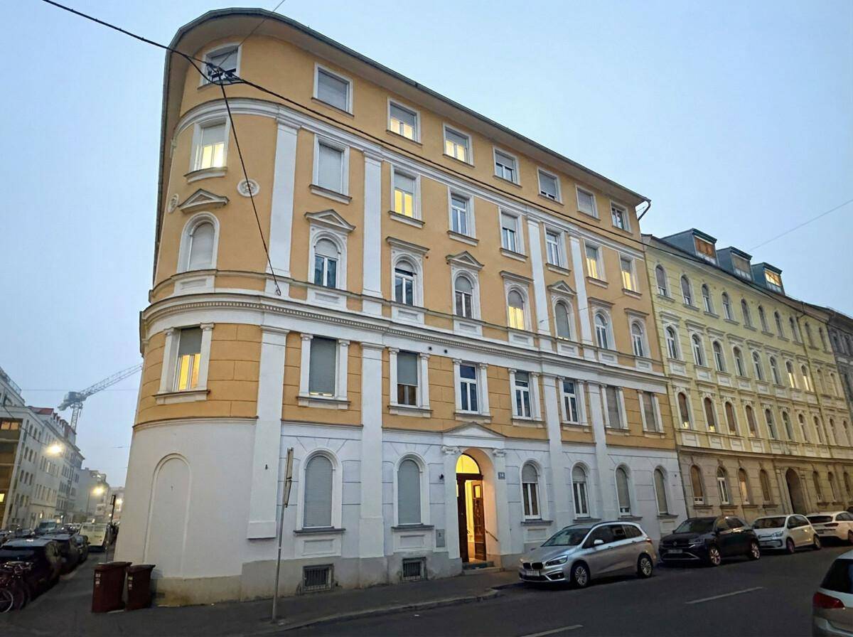 Historisches Eckgebäude mit gelber Fassade und vielen Fenstern an einer Stadtstraße.