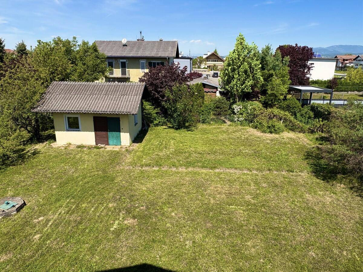Großer grüner Gartenbereich mit Rasenfläche und einem kleinen Gartenhaus im Hintergrund.