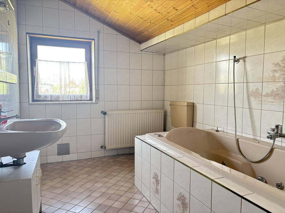 Badezimmer mit Badewanne, Waschbecken und Fliesen im Stil der 80er Jahre.
