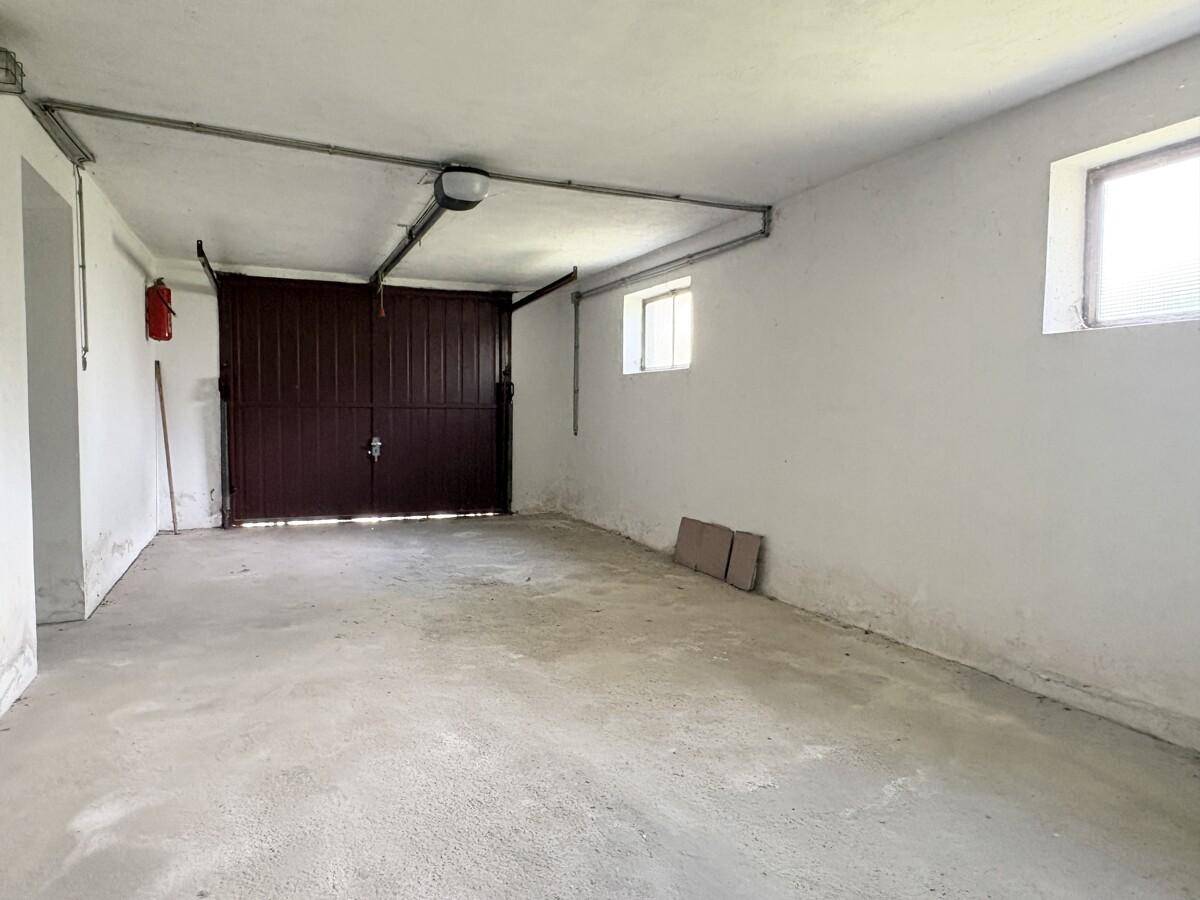 Geräumige Garage mit Betonboden und zwei Fenstern für Tageslicht.