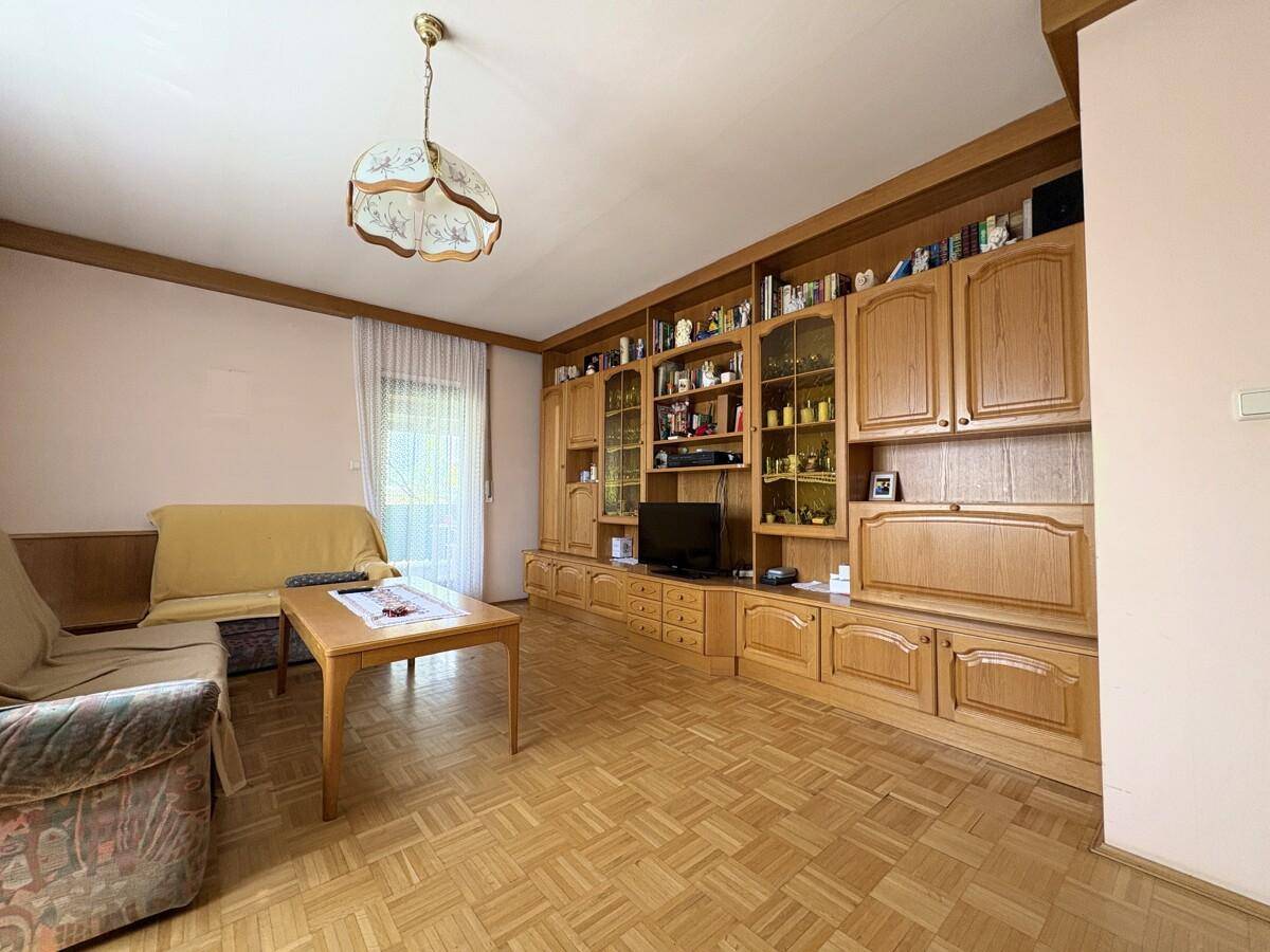 Geräumiges Wohnzimmer mit Parkettboden, großer Schrankwand und traditionellen Möbeln.