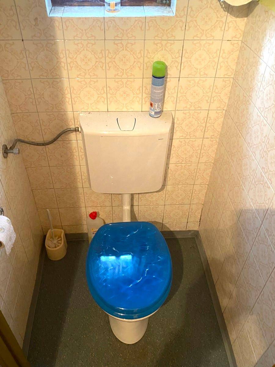 Kleines WC mit Toilette und hellen Fliesen an den Wänden.