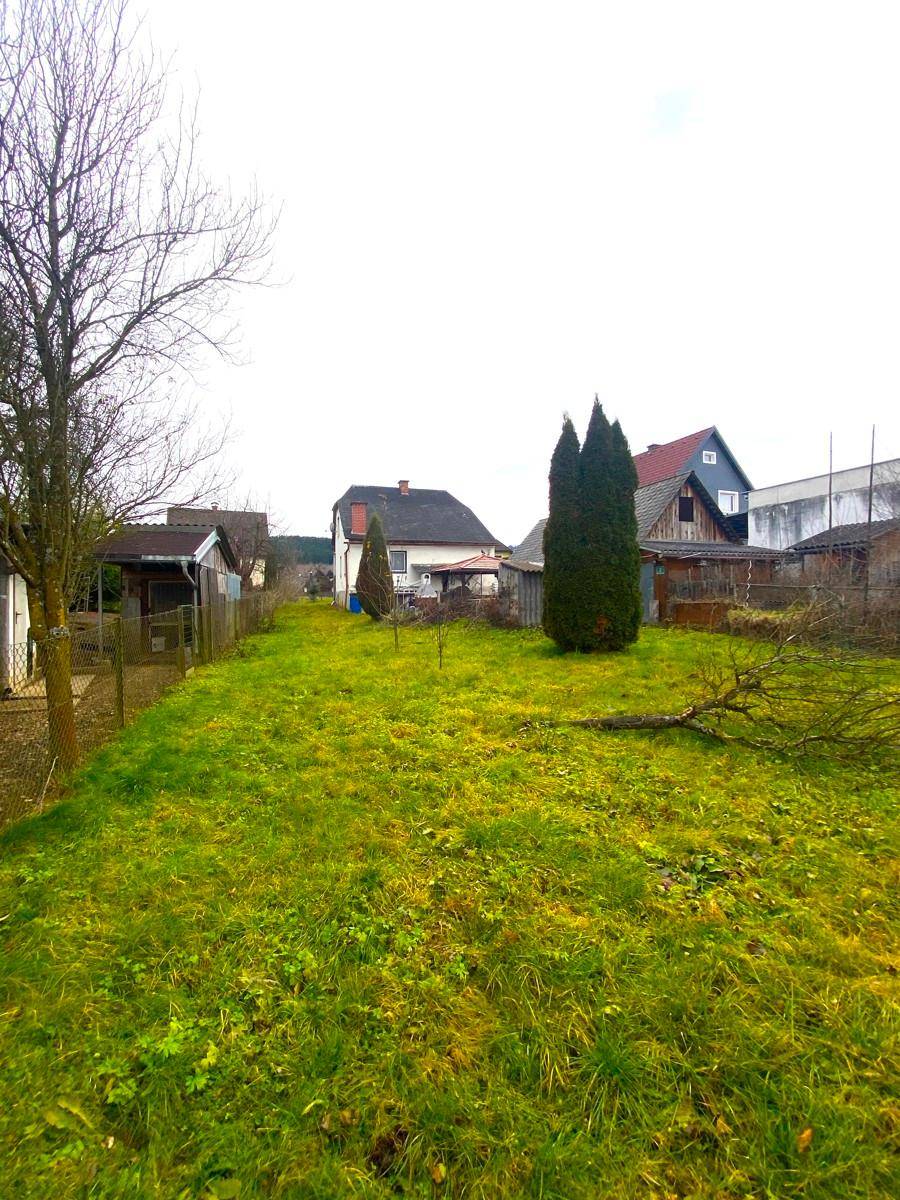 Weitläufiger grüner Gartenbereich mit Rasenfläche und Blick auf die umliegenden Häuser und Natur.