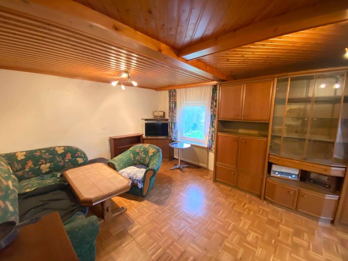 Gemütliches Wohnzimmer mit Holzdecken, Parkettboden und traditionellen Möbeln.