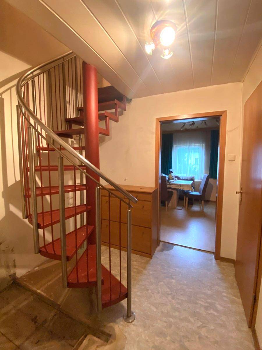 Flur mit auffälliger roter Wendeltreppe und Zugang zu weiteren Räumen.