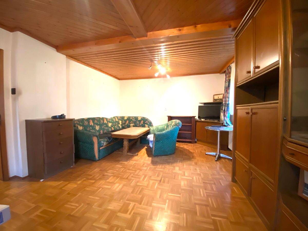 Geräumiges Wohnzimmer mit Holzdecke, Parkettboden und klassischer Einrichtung.