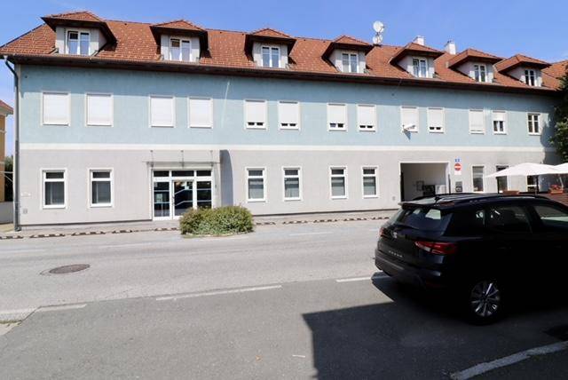 Ansicht eines mehrstöckigen Gebäudes mit hellblauer Fassade, roten Dachziegeln und vielen Dachgauben.
