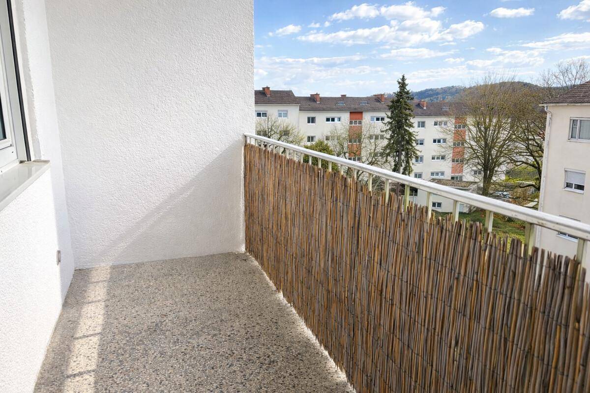 Kleiner Balkon mit Bambusverkleidung und Blick ins Grüne.