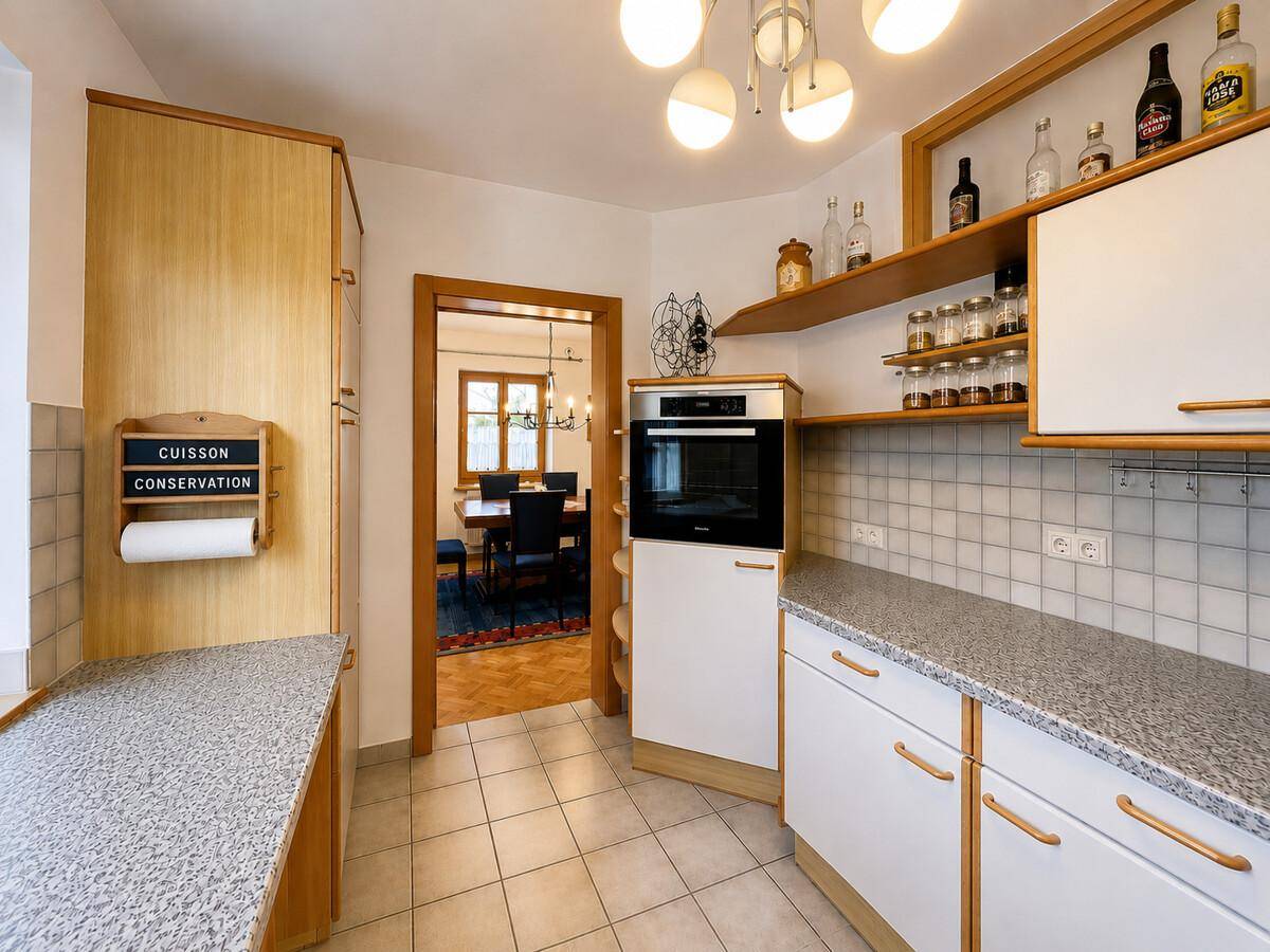 Funktionale Küche mit hellen Holzschränken, Granitarbeitsplatte und Blick in den Essbereich.