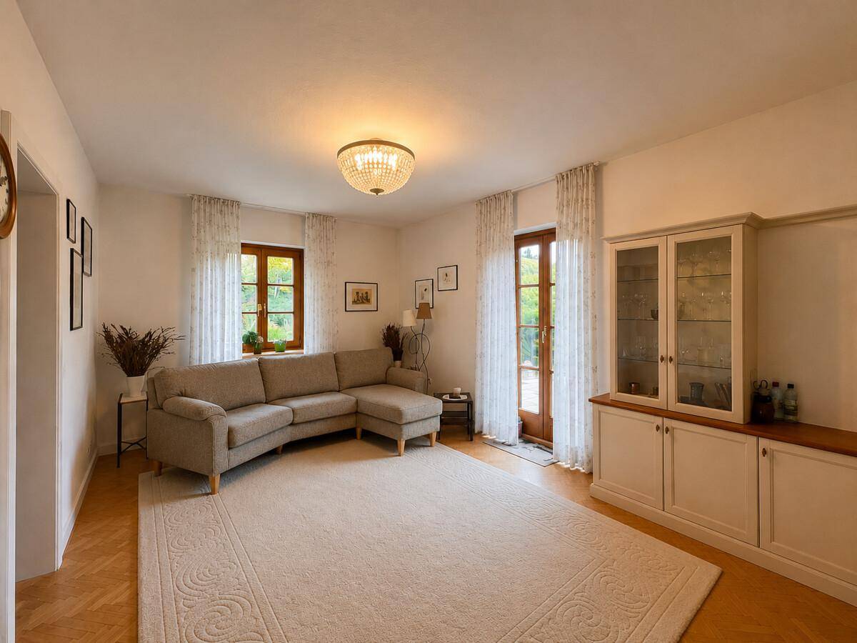 Helles Wohnzimmer mit großem Sofa, Parkettboden und Zugang zur Terrasse.