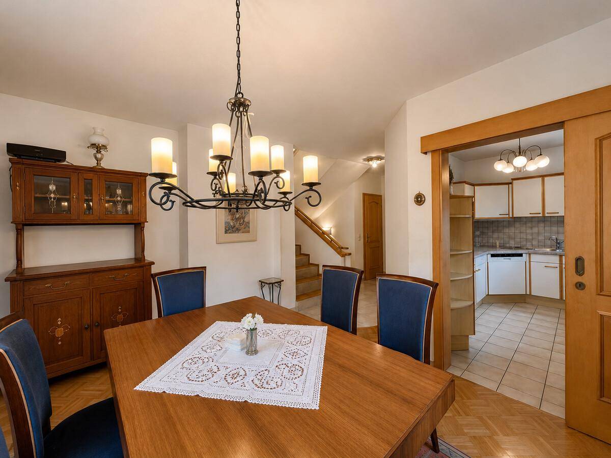 Eleganter Essbereich mit Holztisch, blauen Stühlen und Zugang zur Küche.