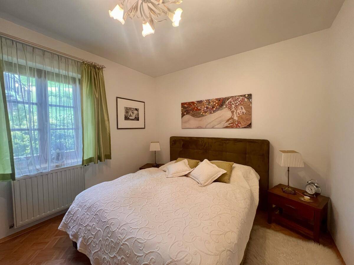 Gemütliches Schlafzimmer mit Doppelbett, Parkettboden und Blick ins Grüne.
