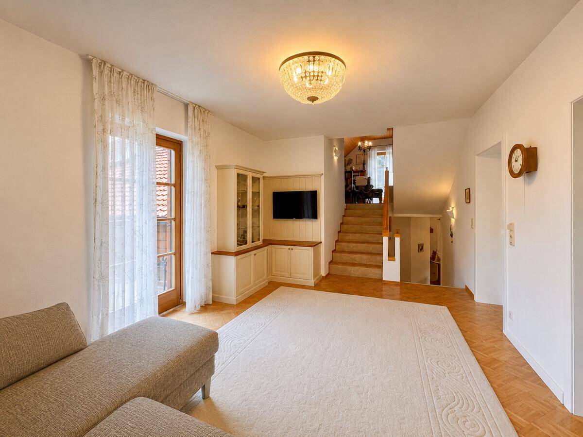 Geräumiges Wohnzimmer mit Parkettboden, Einbauschrank und Treppenaufgang.