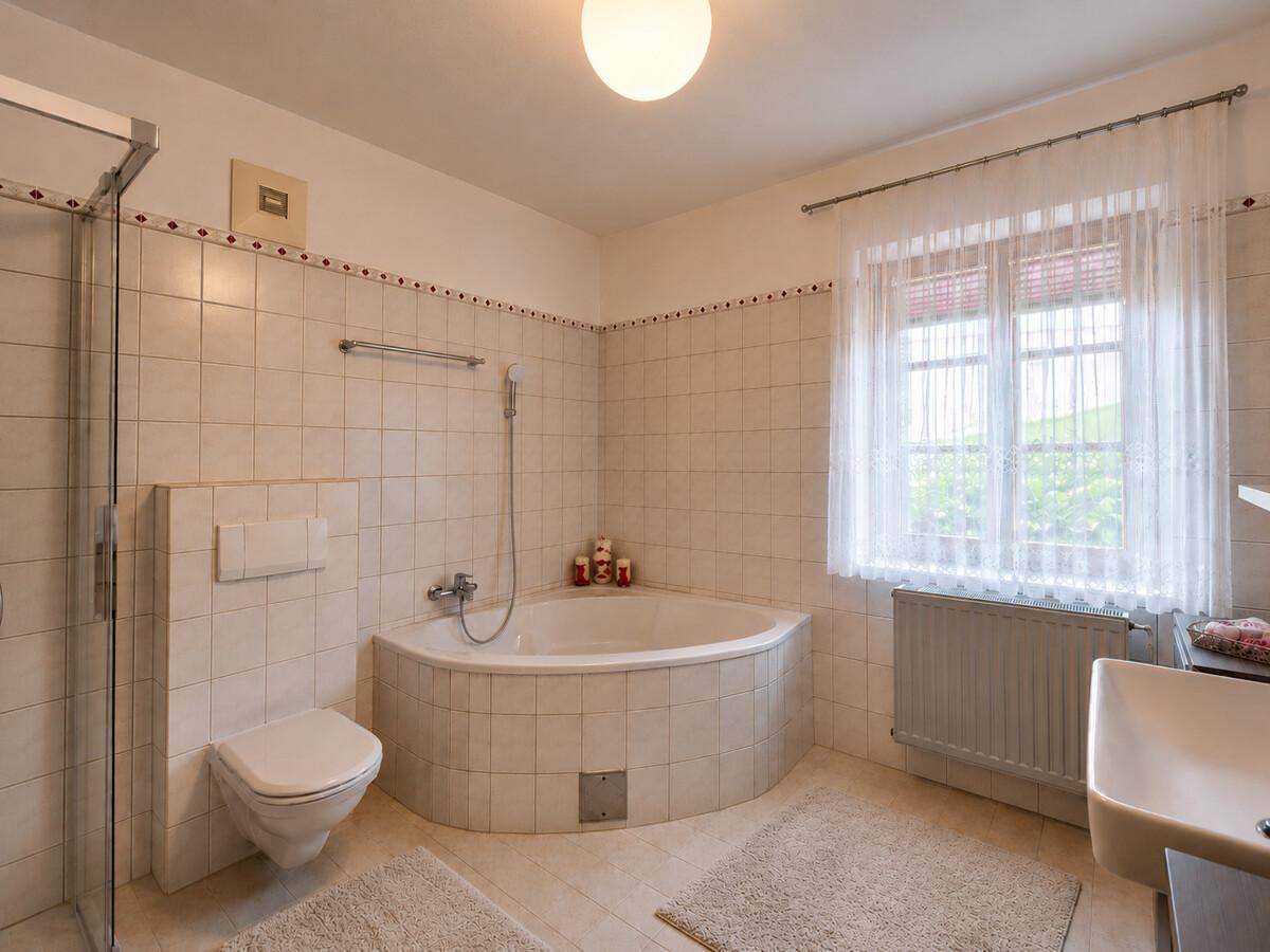 Helles Badezimmer mit Eckbadewanne, Dusche und weißen Fliesen.