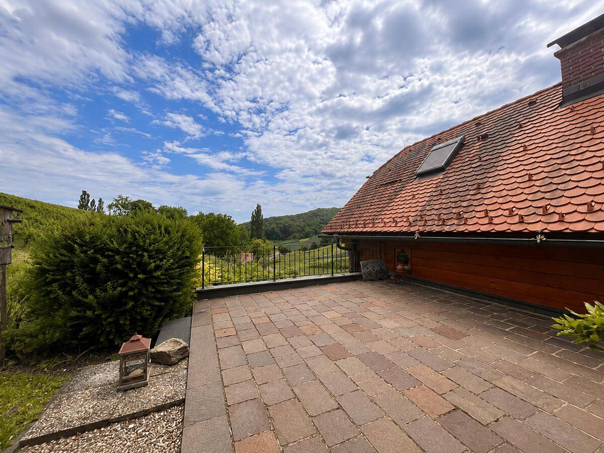 Geräumige Terrasse mit Ziegeldach und Panoramablick über die Weinberge.