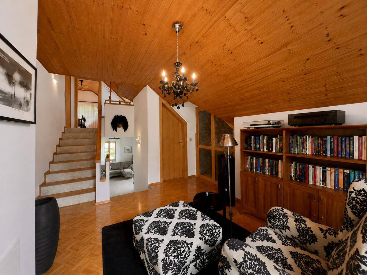 Gemütlicher Wohnbereich im Dachgeschoss mit Holzdecke, Bücherregal und Parkettboden.