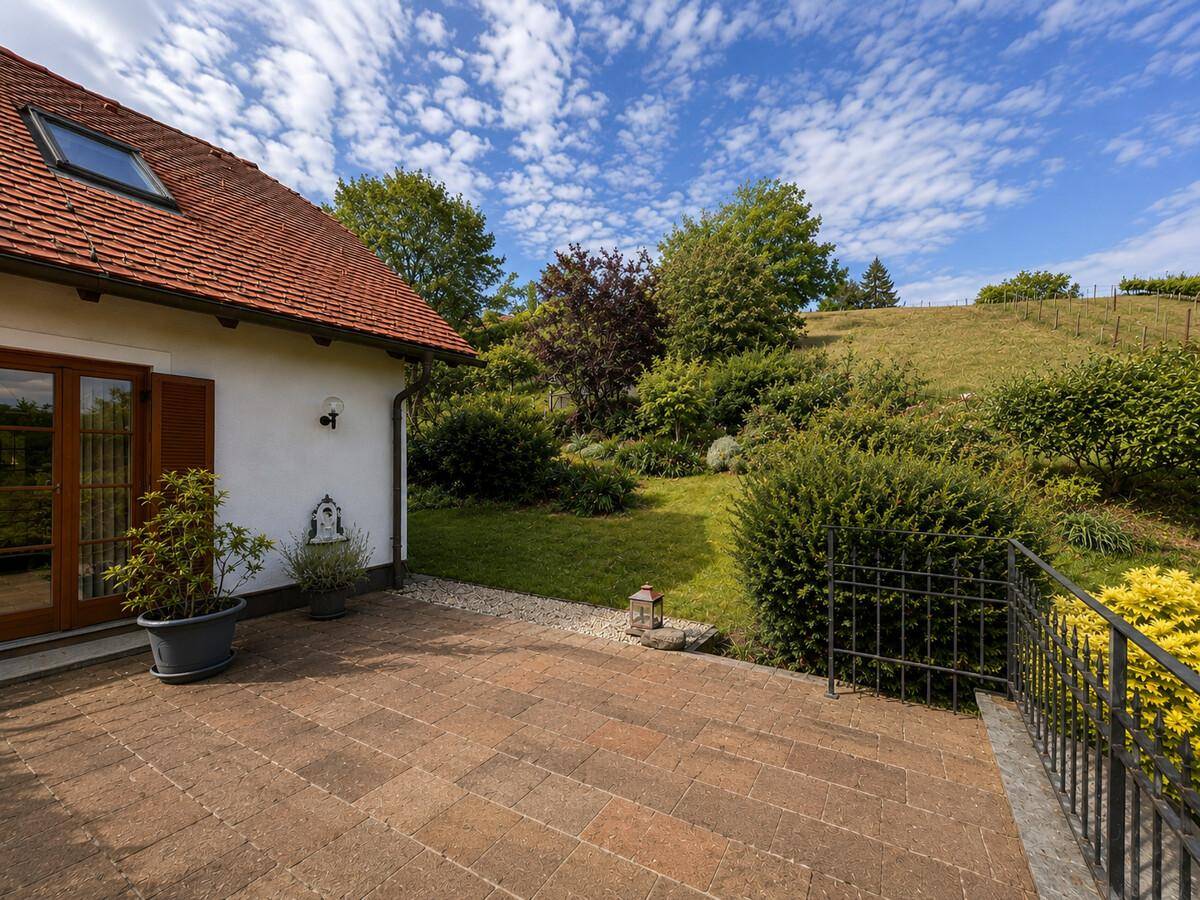 Gepflasterte Terrasse mit Blick auf den Garten und die umliegende Landschaft.