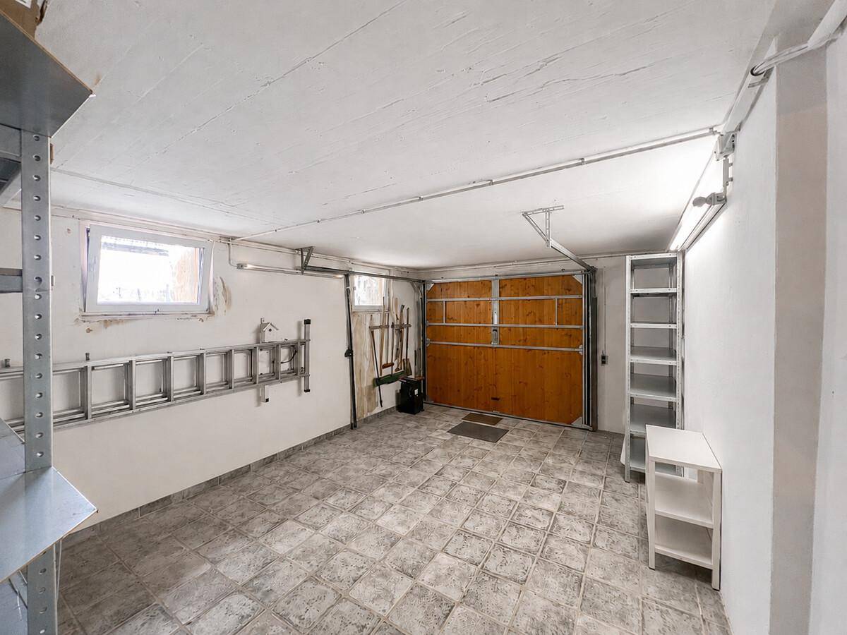 Geräumige Garage mit Betonboden, Regalen und direktem Zugang zum Außenbereich.