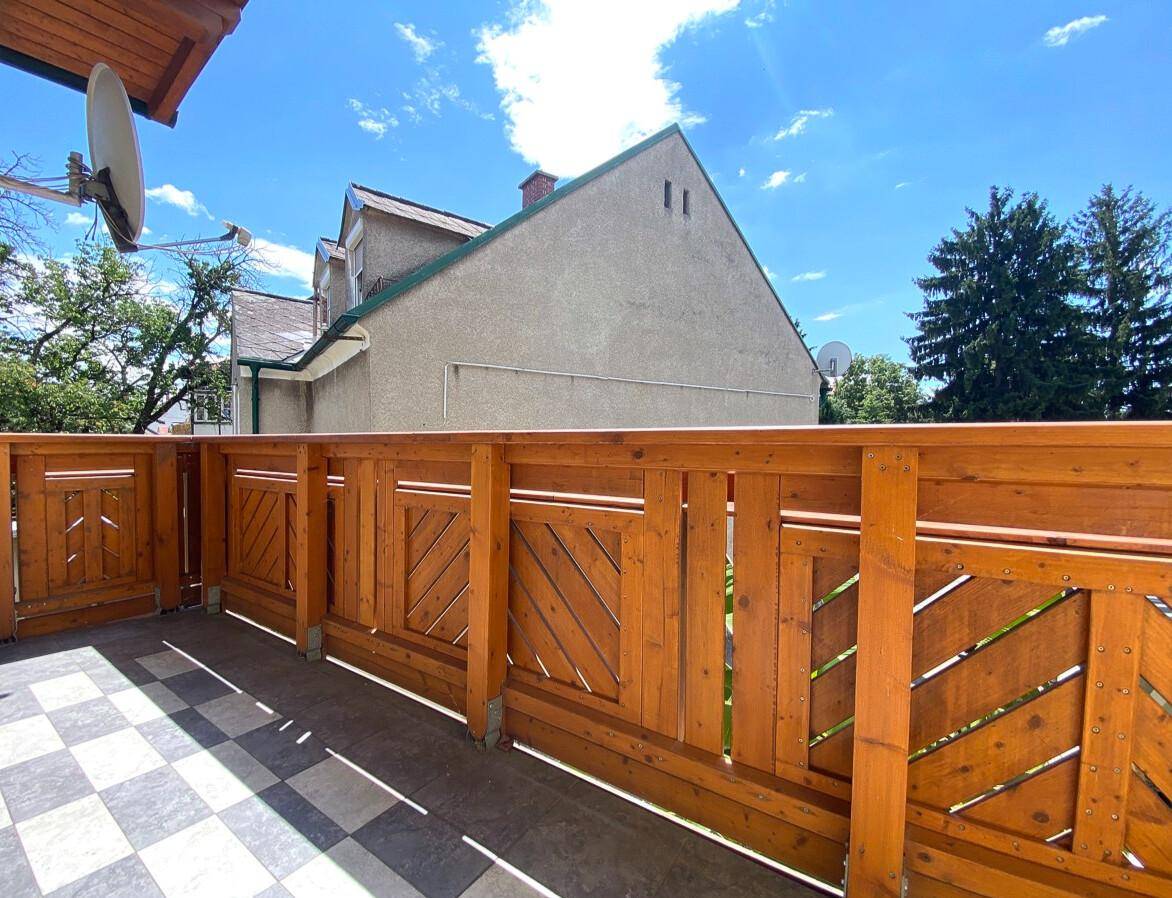 Balkon mit Holzbalkonbrüstung und Fliesenboden, ideal für entspannte Stunden im Freien.