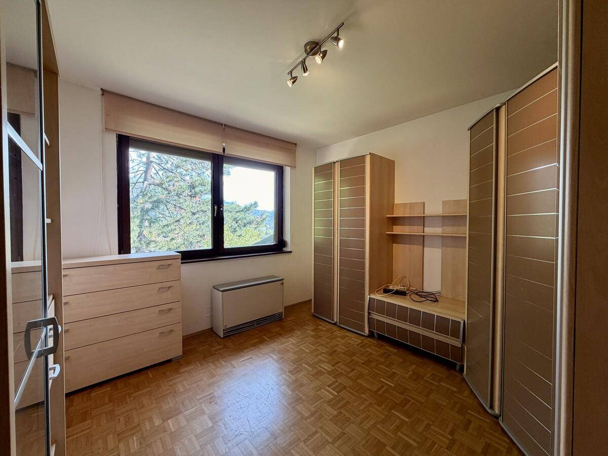 Schlafzimmer mit Parkettboden, hellen Holzmöbeln und großem Fenster mit Ausblick.