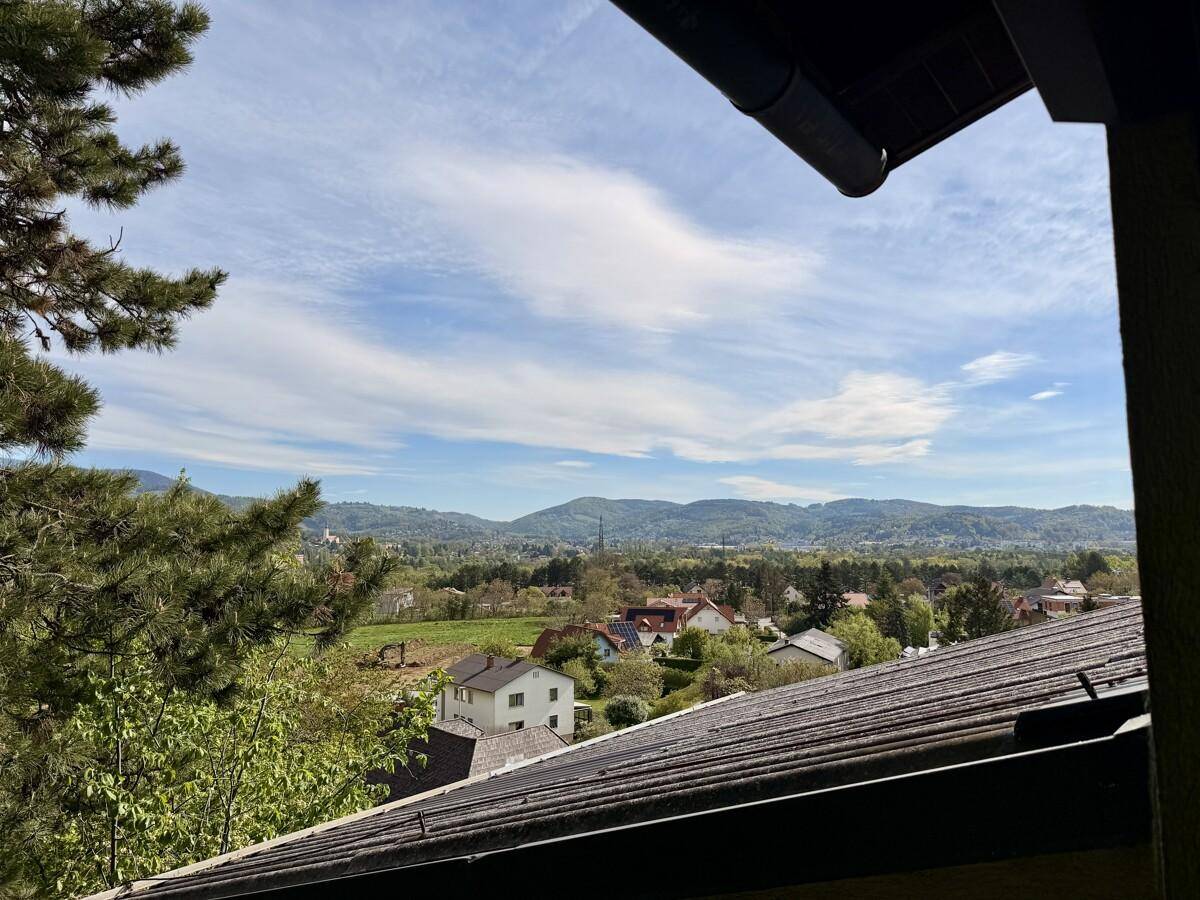 Weitläufiger Ausblick über die hügelige Landschaft und umliegende Häuser unter blauem Himmel.
